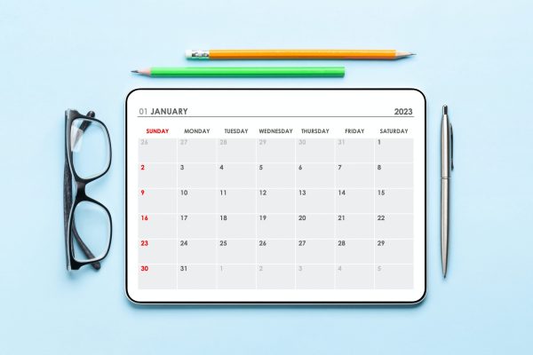 Tablet with calendar app, eyeglasses and office supplies